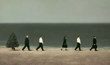 bankers walking on a beach by a Christmas tree