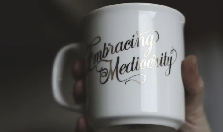 A mug that says "embracing mediocrity" 