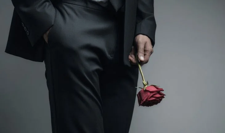 a man holding a red rose 